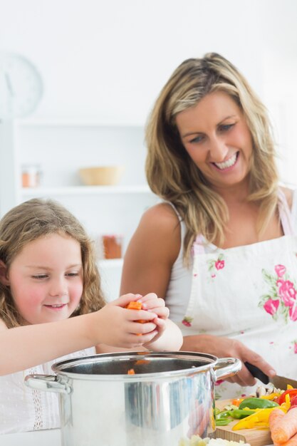 Laughing mother and daughter preparing vegetables