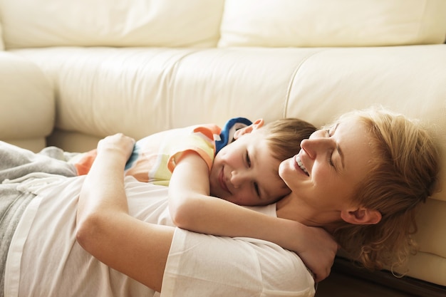 Laughing mother and son in embrace at home during sunny day