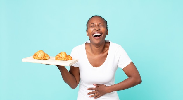 Laughing out loud at some hilarious joke and holding a croissant tray