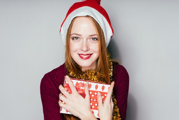 Laughing red-haired girl in a red cap celebrates the new year 2018, received a Christmas gift