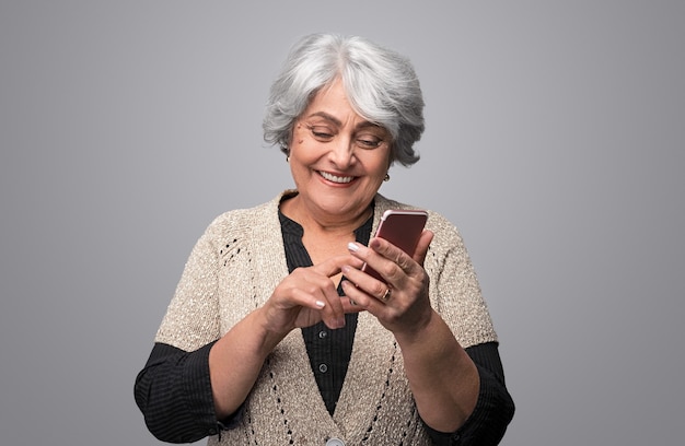 Laughing senior lady using smartphone