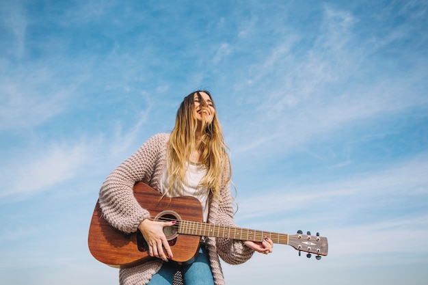 Смеющаяся женщина, играющая на гитаре в природе