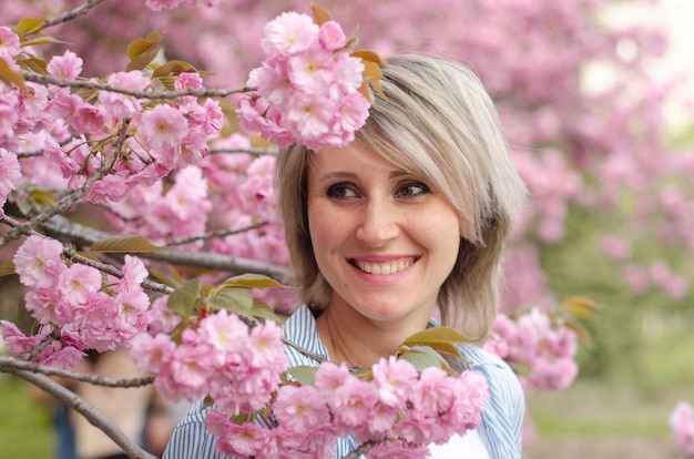 Laughing woman with pink hair near sakura flowers