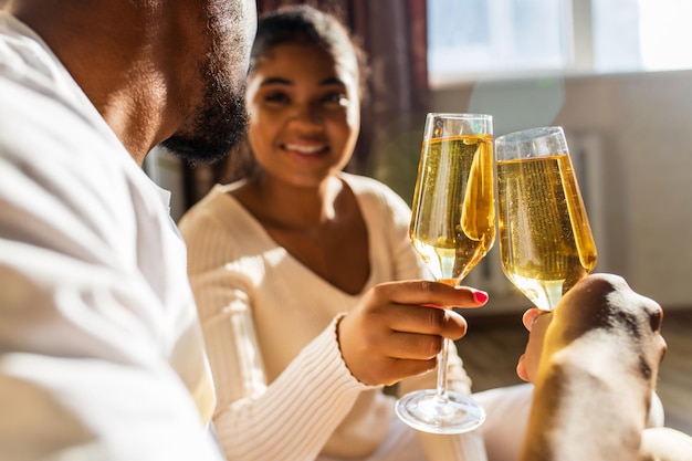 Ridendo giovane coppia etnica afro incontri con champagne a casa mentre si siede al pavimento caldo