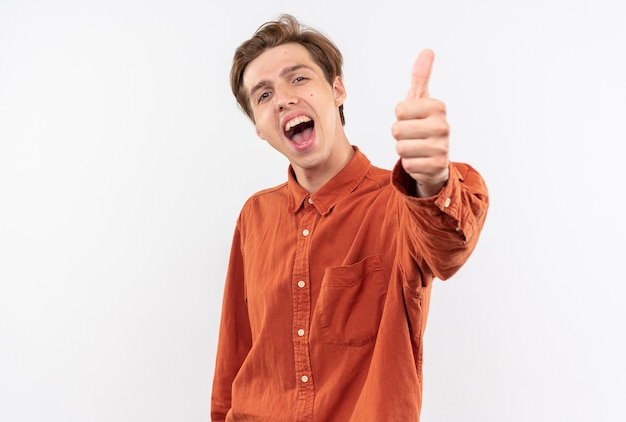 laughing young handsome guy wearing red shirt showing thumb up isolated on white wall