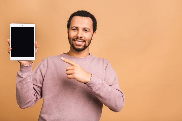 Laughing Young man Holding a Touch Pad Tablet PC on Isolated over beige.