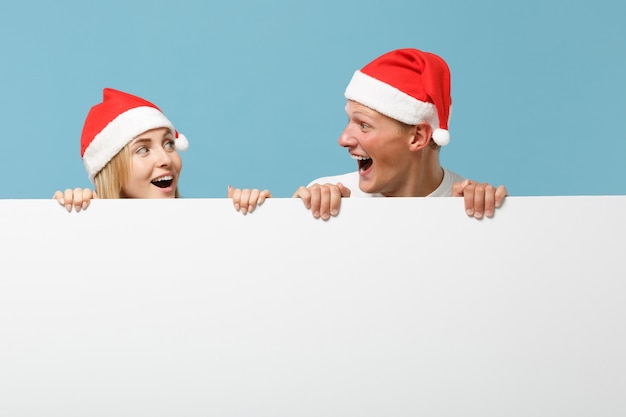 Laughing young Santa couple friends guy and woman in Christmas hat 