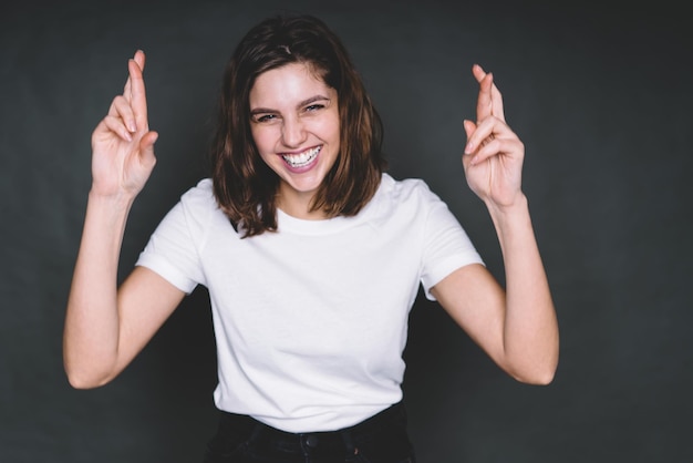 Photo laughing young woman crossing fingers