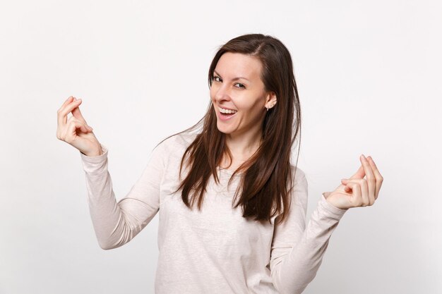 Laughing young woman in light clothes rubbing fingers showing cash gesture asking for money isolated on white wall background in studio. People sincere emotions, lifestyle concept. Mock up copy space.