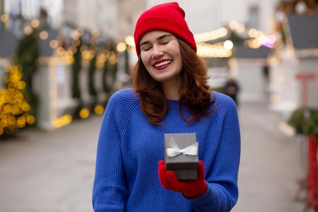 Ridendo giovane donna che riceve un regalo in una scatola alla fiera di natale