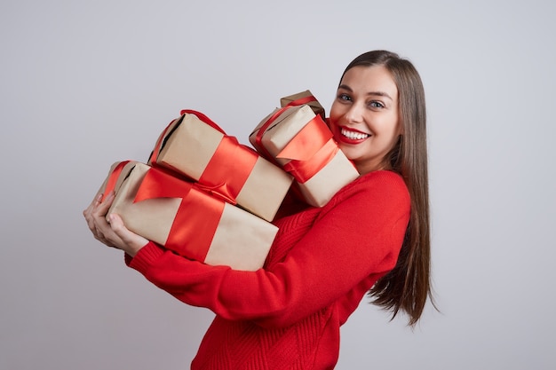 Laughing young woman in a red sweater holding a few falling gift box