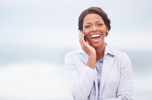 Laughter in the ocean breeze A pretty african american woman having an enjoyable conversation while outdoors