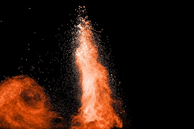 Launched orange color powder explosion on black background. 