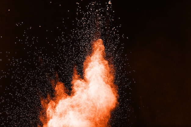 Launched orange color powder explosion on black background. 