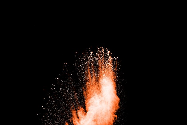 Launched orange color powder explosion on black background. 