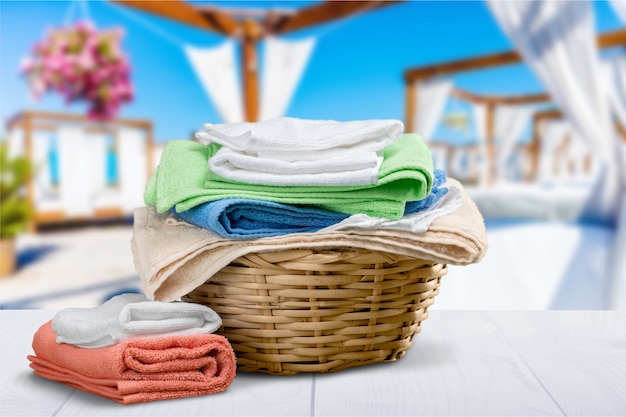 Laundry basket with colorful towels on background