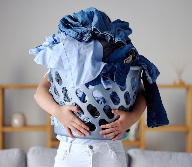 Photo laundry clothes and woman with basket for cleaning housework and carry washing in living room housekeeping service spring clean and cleaner in apartment with heavy clothing fabric and material