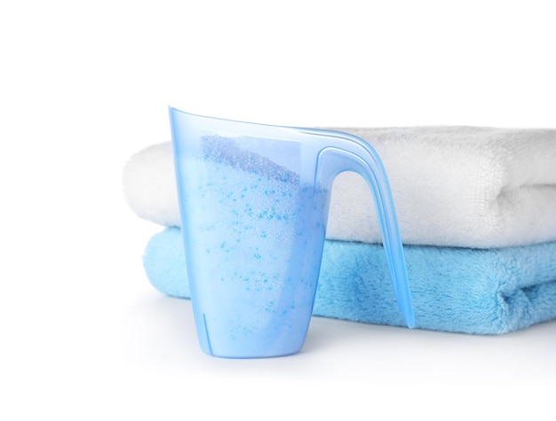 Laundry detergent in plastic measuring cup and towels on white background  Stock Photo by ©NewAfrica 305694190