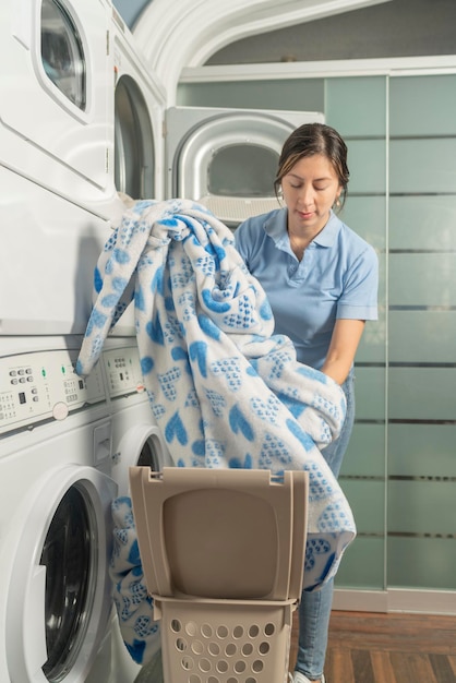 Laundry employee putting a bed blanket into the washer