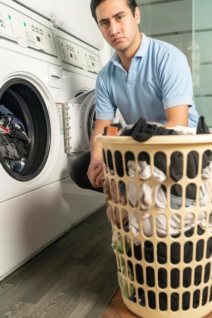 Laundry employee putting clothes in the washing machine and\
looking at the camera