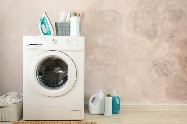 Laundry room with washing machine against light brown wall