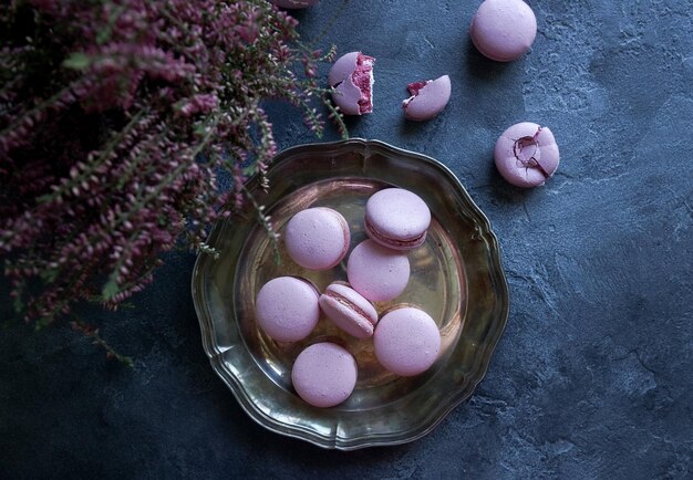 Lavander and blueberry macarons and cappuccino coffee on dark stone table with lilac flowers