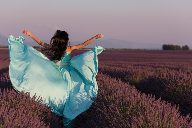 lavander flower field woman in cyand dress having fun and relax on wind in  purple flower field