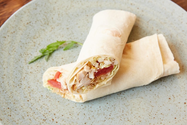 Foto rotolo di lavash con pollo e verdure si chiuda su un piatto orizzontale