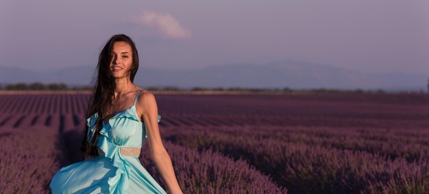 Lavendel bloemenveld vrouw in cyaan jurk met plezier en ontspannen op de wind in paars bloemenveld