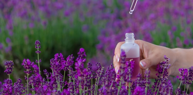 Lavendel etherische olie fles op houten tafel en bloemen veld achtergrond