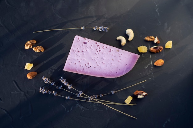 Lavender cheese with nuts on a black board, flat lay