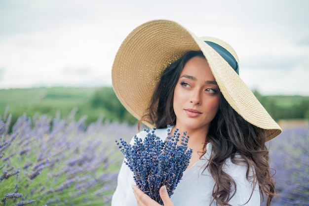 Lavender field Beautiful darkhaired curly woman in white simple dress in field of purple flowers