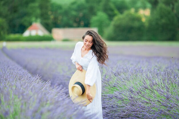 Lavender field beautiful darkhaired curly woman in white simple dress in field of purple flowers