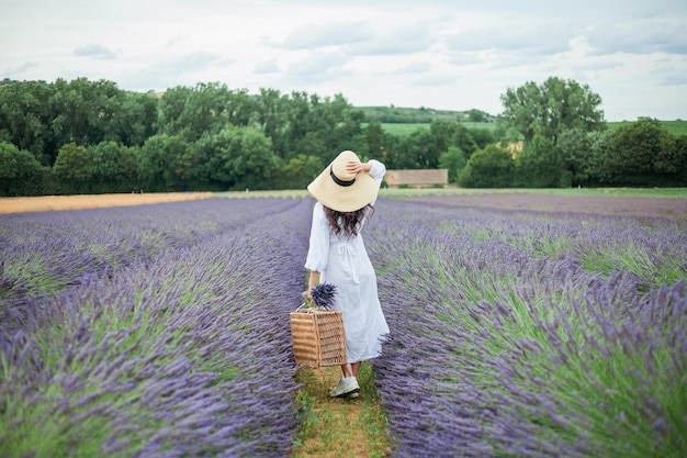 Lavender field Beautiful darkhaired curly woman in white simple dress in field of purple flowers