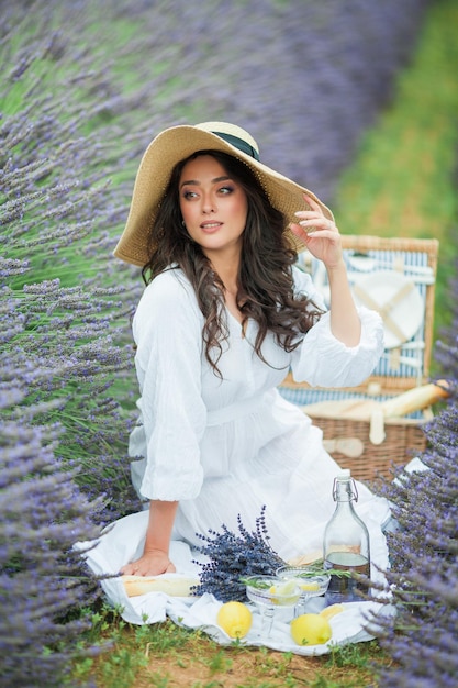 Lavender field Beautiful darkhaired curly woman in white simple dress in field of purple flowers