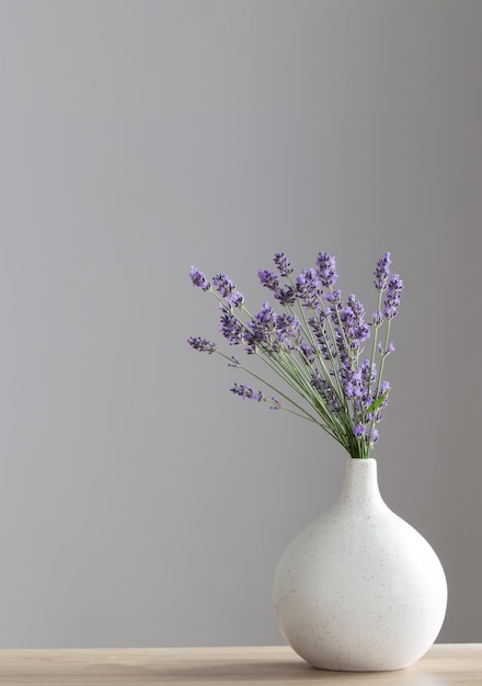 Lavender flowers in ceramic vase on gray background