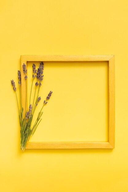 Lavender flowers and golden frame on yellow background top view Copy space Vertical photo