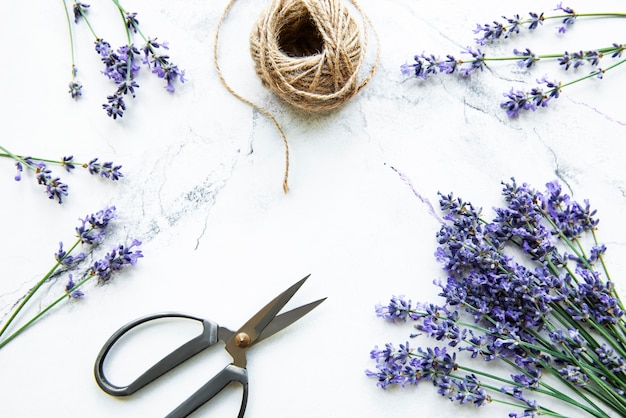 Lavender flowers, scissors and rope on a white marble