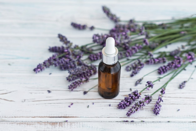 Lavender herbal oil and lavender flowers on grey wooden