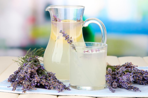 Lavender lemonade in glass jug on napkin on bright background