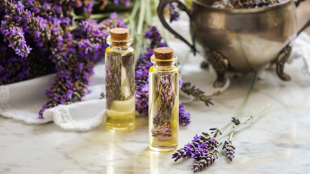 Lavender oil bottles, natural herb cosmetic with lavender flowers on stone background