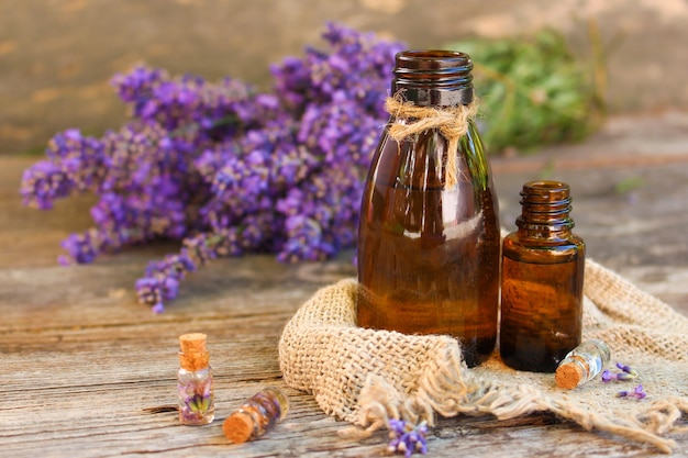 Lavender oil in different bottles on wooden background.