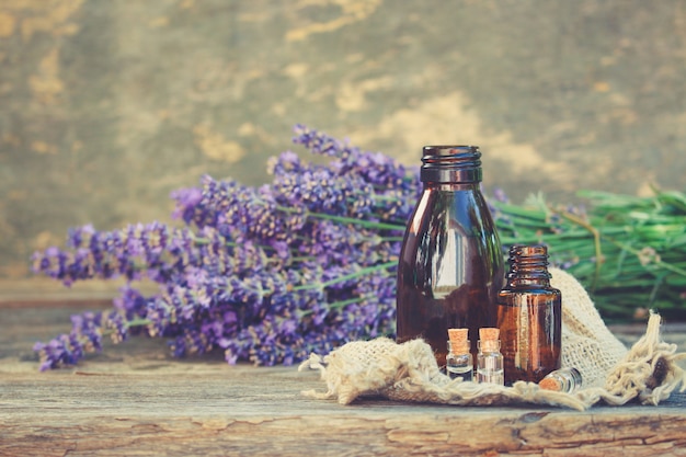 Lavender oil in different bottles on wooden background.