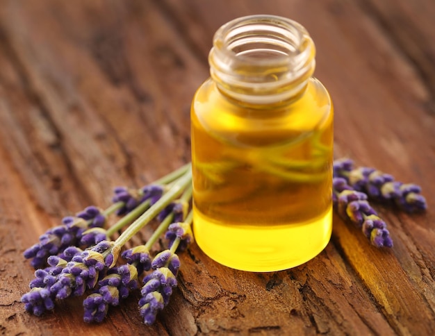 Lavender oil with flower on wooden surface