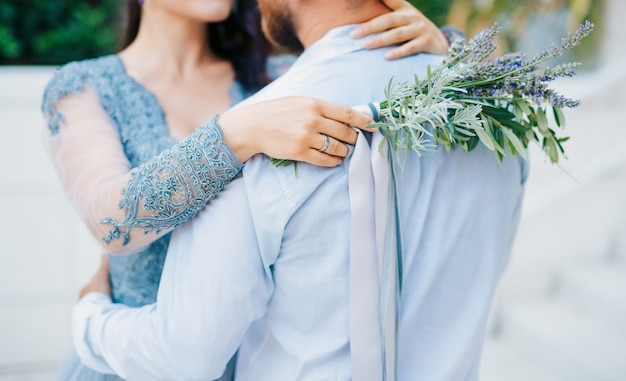 Bouquet da sposa lavanda nelle mani della sposa in abito biancoblublue