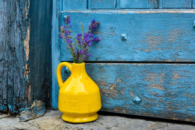 Lavender in a yellow kouvinum on a background of blue shabby door