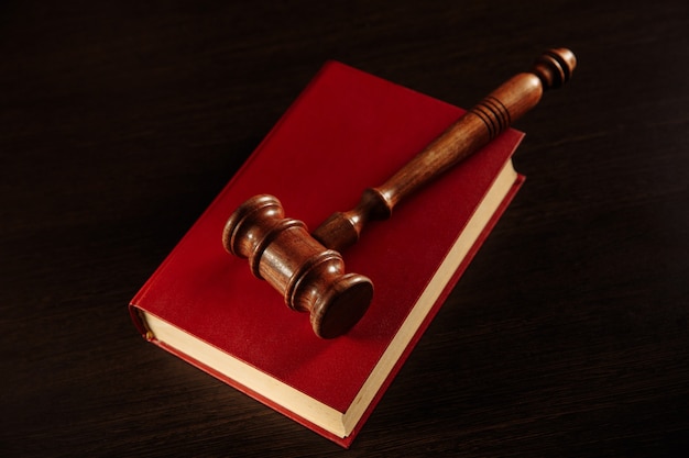 Law book with a judges gavel resting on top of the pages in a courtroom or law enforcement office.