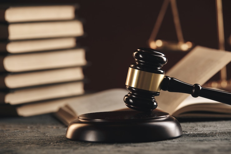 Photo law concept - open law book with a wooden judges gavel on table in a courtroom or law enforcement office on black background.