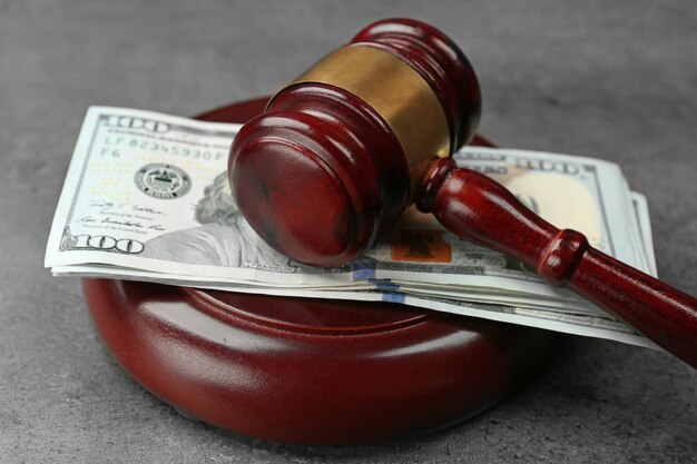 Law gavel with dollars on grey background closeup