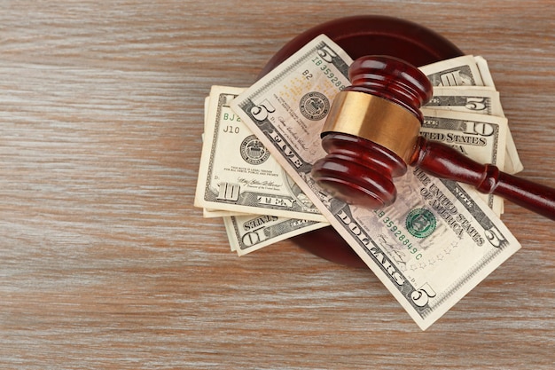 Law gavel with dollars on wooden table background closeup